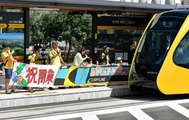 特別列車の到着を横断幕で祝う祖母井保育園の園児ら＝26日午後１時20分、芳賀町下高根沢