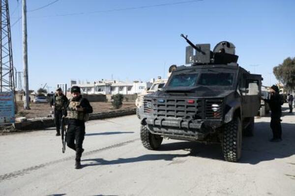 20日、シリア北東部ハサカ県で、装甲車両のそばを歩くシリア民主軍(SDF)の戦闘員ら(ロイター=共同)