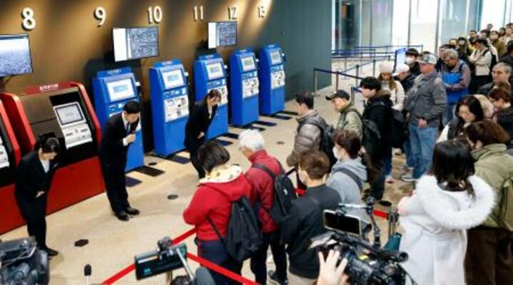 訪れた観光客に向かい「天望デッキ」の営業再開をアナウンスする東京スカイツリーの従業員(左奥)=26日午前、東京都墨田区