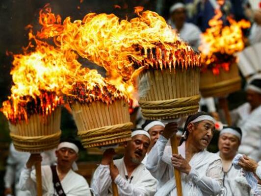 「那智の扇祭り」で、燃えさかる大たいまつを担ぎ練り歩く白装束の氏子ら=14日午後、和歌山県那智勝浦町