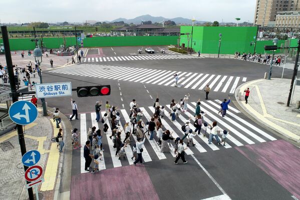 東京・渋谷のスクランブル交差点を再現したオープンセットの横断歩道を渡る園児や保護者ら＝６日午前10時25分、足利市五十部町、ドローンから