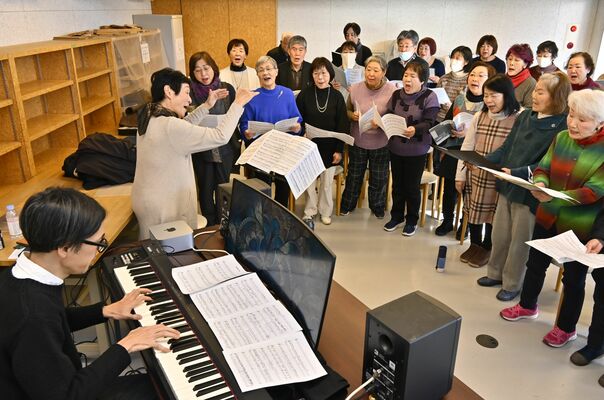 石田さん（左）の伴奏で合唱を練習する町民ら