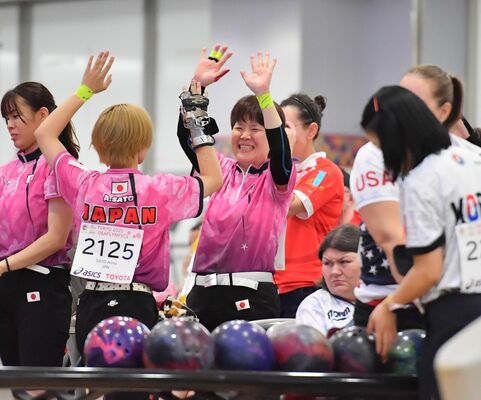 ストライクを決めた仲間をハイタッチで祝福する村野（中央）＝東大和グランドボウル、伊藤慧撮影