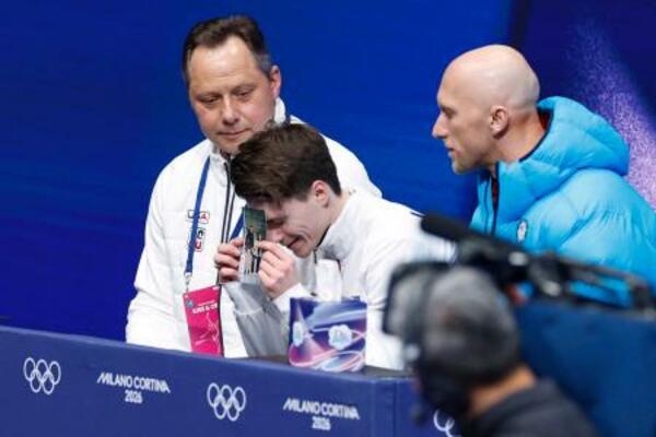 　男子ＳＰの得点を確認し、亡き両親の写真に額をつけるマキシム・ナウモフ＝ミラノ（共同）