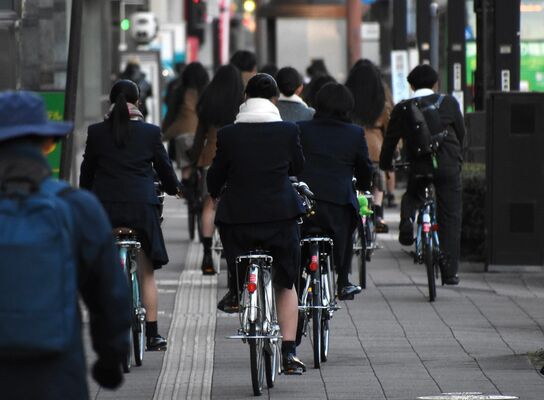自転車に乗る高校生ら。ヘルメットを着用した姿は少ない＝９日午後、宇都宮市本町