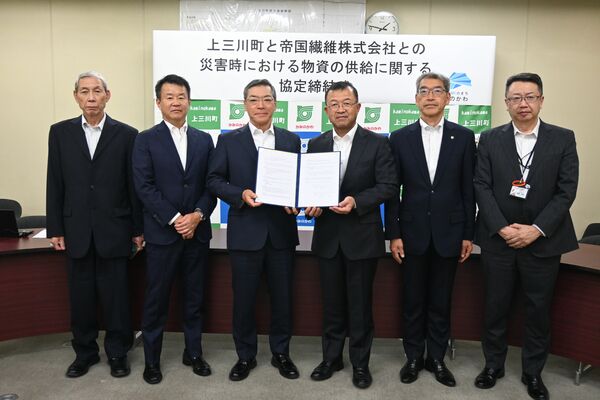 協定書を手にする星野町長（右から３人目）と桝谷社長（同４人目）＝上三川町役場