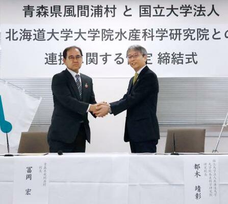 協定締結式で握手する、青森県風間浦村の冨岡宏村長(左)と北海道大大学院水産科学研究院の都木靖彰研究院長=3日午前、北海道函館市