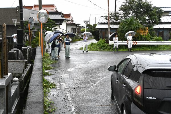 屈曲した県道の現場を確認する関係者