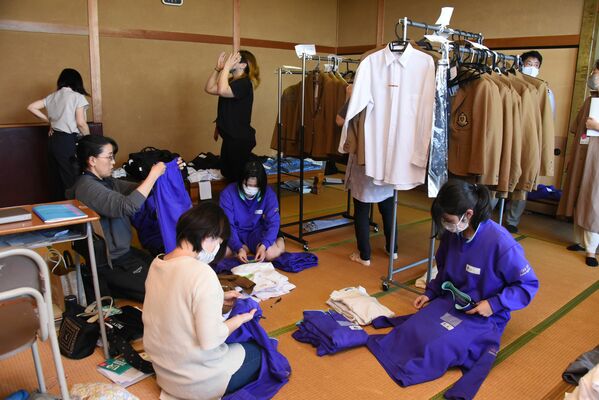 集まった制服などの仕分けをする保護者と生徒
