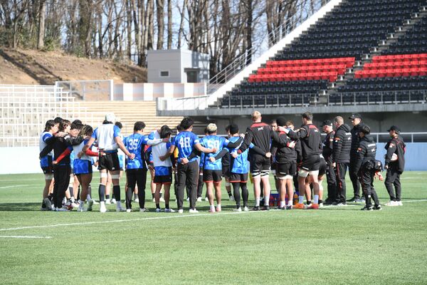 練習後に円陣を組むホンダヒートの選手ら。本県初戦に向け、黒色の観客席の一部が赤色に変えられた=22日午前、ホンダヒート・グリーンスタジアム