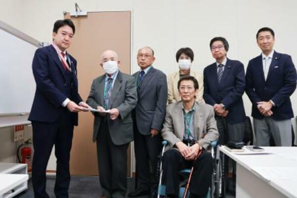 警察庁の担当者に要請文を手渡す「犯罪被害補償を求める会」の藤本護代表理事(左から2人目)=29日午前、国会