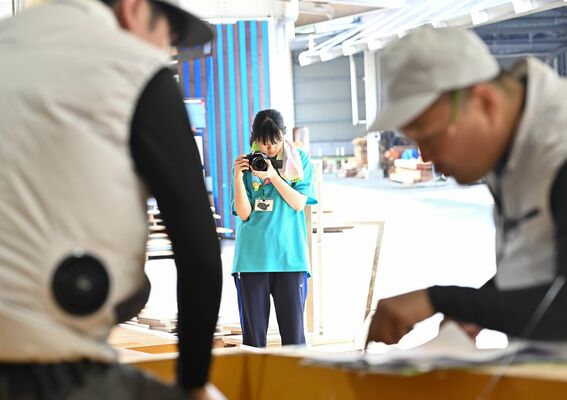 組み立ての作業員（手前）を撮影する生徒