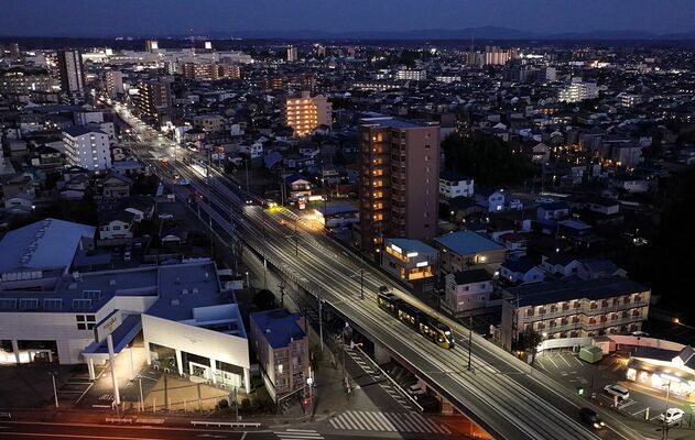 日が暮れ明かりがともる市街地を行き交うＬＲＴ。開業から１年が過ぎ県都に溶け込んでいる＝30日午後５時10分、宇都宮市東宿郷５丁目、ドローンから、磯真奈美撮影