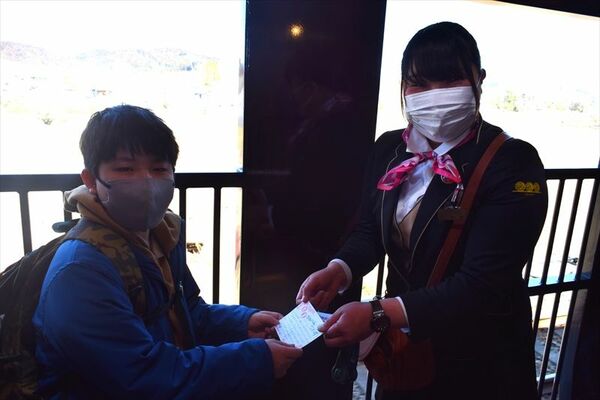 ＳＬ観光アテンダントの井池さん（右）から記念カードを受け取る篠原海吏さん（左）