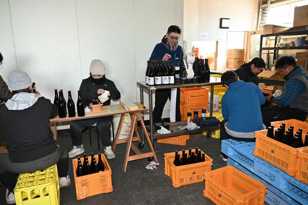 ロウ付け、ラベル貼りの出荷最終作業を行う岩崎さん（右）とボランティア＝１１日午後、足利市