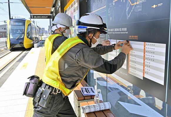 停留場で新しい時刻表を貼り付ける作業員＝30日正午、宇都宮市東今泉１丁目