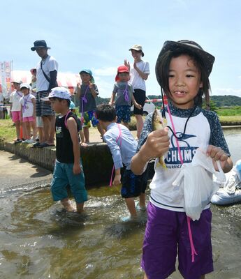 捕まえたアユを手に笑顔の小学生