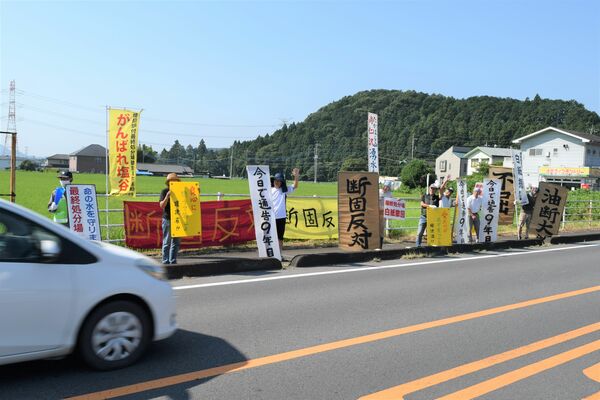 通行する自動車などに白紙撤回を求める姿勢をアピールする町民ら＝30日午前、塩谷町玉生