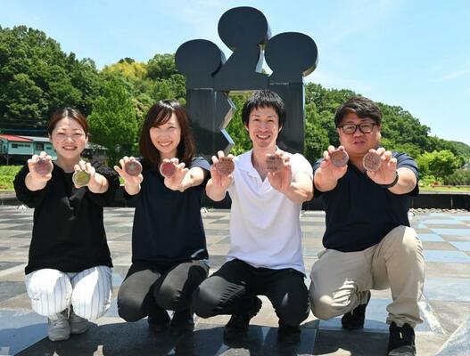 モニュメントの前で陶板を持つ当時小学生だった町職員