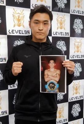 ボクシングIBFスーパーバンタム級での再起戦を発表し、対戦相手の写真を手にポーズをとる西田凌佑=18日、大阪市住吉区