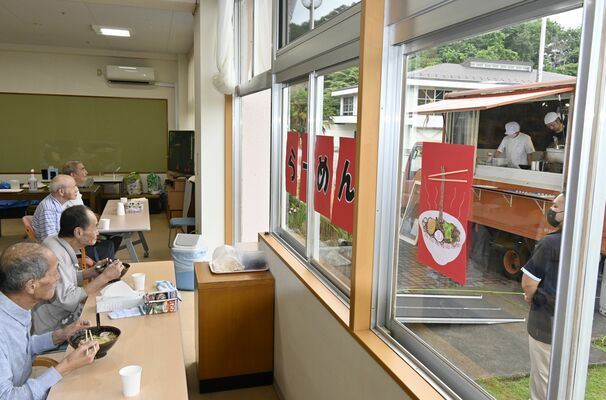目の前で調理されたラーメンを食べる利用者ら