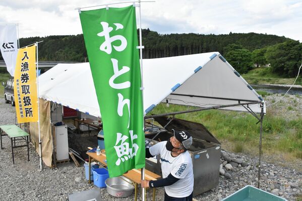 那珂川河川敷におとりアユ販売用のテントを準備するおとり店の関係者＝30日夕、大田原市黒羽向町