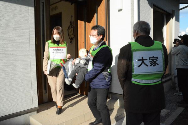 訓練で子ども役の人形を連れ出す児相職員ら＝７日午後２時20分、宇都宮市若草２丁目