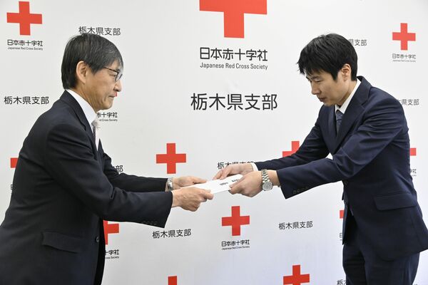 日赤県副支部長の岩佐氏（右）に救援募金の目録を手渡す若菜社長＝11日午前、宇都宮市若草１丁目