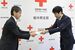 日赤県副支部長の岩佐氏（右）に救援募金の目録を手渡す若菜社長＝11日午前、宇都宮市若草１丁目