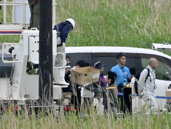 コウノトリのひなを入れた段ボール(中央下)を高所作業車から降ろす作業員ら