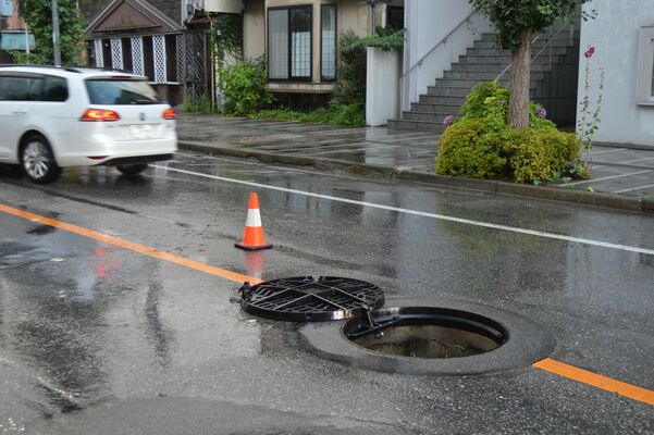 大雨の影響でマンホールがずれたままの道路＝11日午後６時55分、宇都宮市昭和１丁目