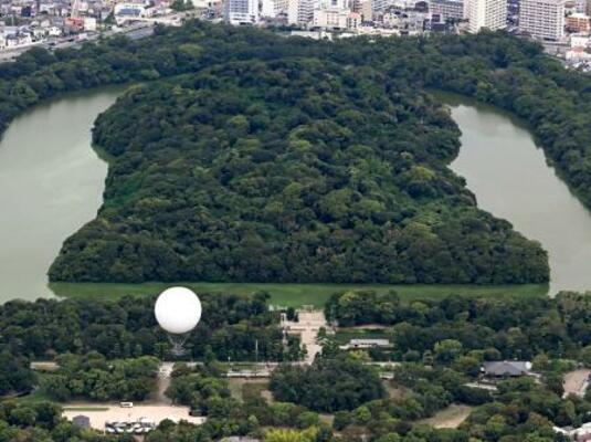 　仁徳天皇陵古墳（奥）近くの大仙公園から浮かび上がったガス気球＝３日午後、堺市（共同通信社ヘリから）
