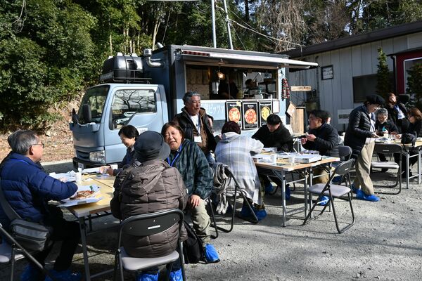 キッチンカーのピザをほおばりながらワインを楽しむ参加者＝１３日午後、宇都宮市