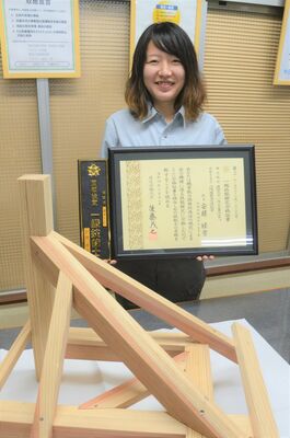 合格証書を手にする安藤さん。手前は試験勉強で制作した木材加工品