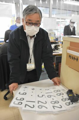 熊本県自動車標板協会で交付されるナンバープレートと松岡史朗事務局長＝熊本市東区