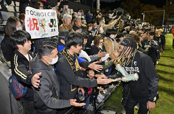 Ｊ２昇格を決め、サポーターとタッチする栃木シティの選手たち（右）＝11月23日の長野戦から、ＣＦＳ