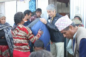 ネパール大地震の被災地支援で村人に毛布を配る半田さん（中央右）＝2016年12月下旬（半田さん提供）