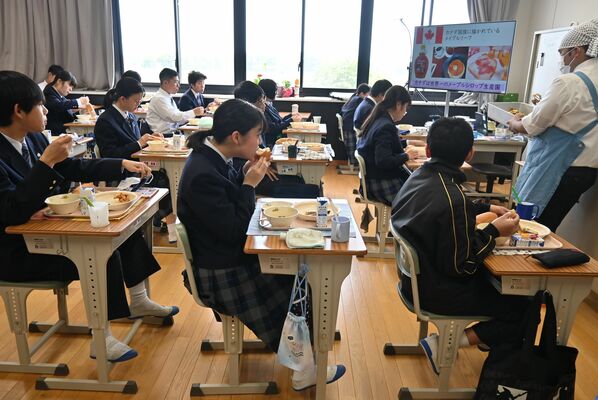 テレビの解説を受けながら給食を食べる生徒