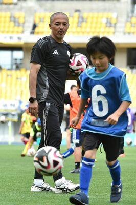 小学生にリフティングを教える小野さん（左）＝22日午後、カンセキスタジアムとちぎ
