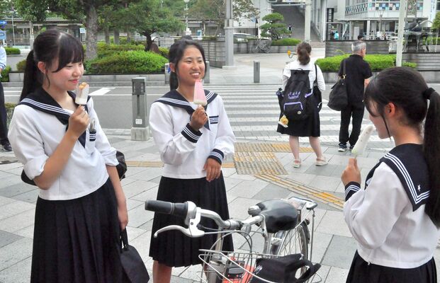 佐野駅前でアイスを食べ、涼む下校途中の高校生たち＝24日午後５時50分、佐野市若松町