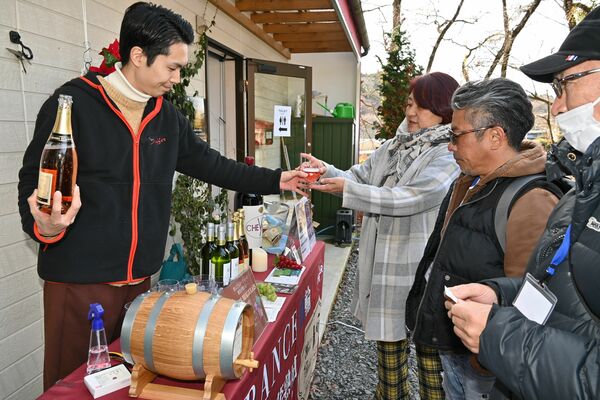 大谷熟成ワインが注がれたグラスを受け取る参加者＝１３日午後、宇都宮市