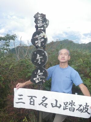 茅ケ岳の山頂で記念の横断幕を掲げる青木さん（青木さん提供）
