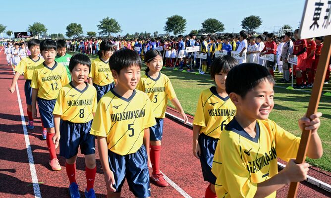 秋空の下、堂々と入場行進する選手たち＝12日午前８時45分、真岡ハイトラ運動公園陸上競技場