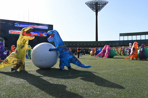 大玉転がしに挑戦する恐竜姿の参加者