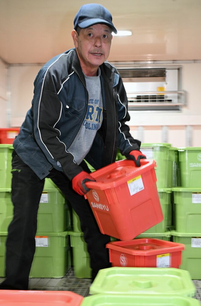 ケーキ、菓子などの材料になる液卵を荷台から下ろす亀山さん＝１月６日午後８時15分、茨城県土浦市、河野光吉撮影
