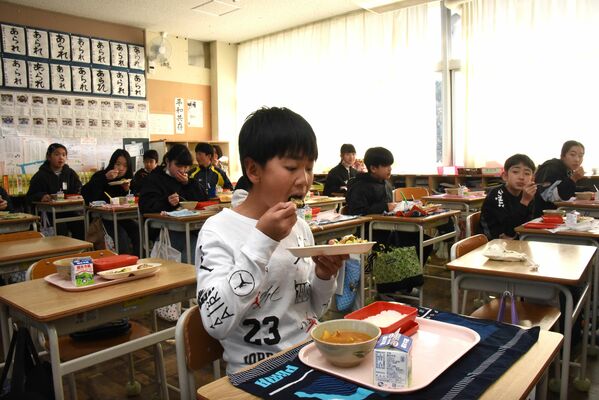 ホタテのハーブ焼きを味わう田野小児童

