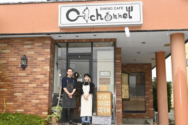 豚の絵の看板を掲げる店構えと柏崎さん夫婦
