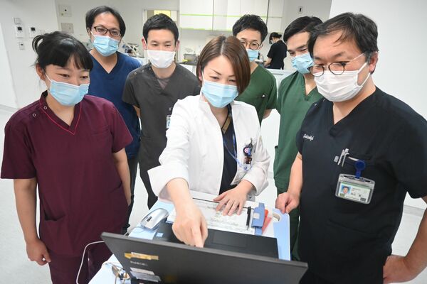 同僚の医師らと話し合う診療看護師の青木さん（中央）＝２０２４年12月中旬、宇都宮市竹林町