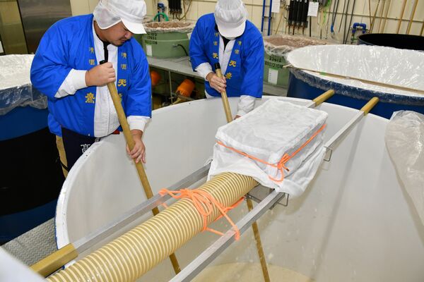 櫂棒を操り仕込み作業を行う蔵人たち=17日午前、大田原市蛭畑