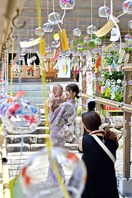 風鈴が並ぶ参道で家族写真を撮影する人たち＝２日午前11時35分、下野市下古山